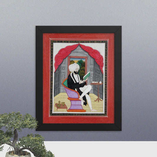 A Sikh Sardar reading from a book, seated in front of a window - Framed Print